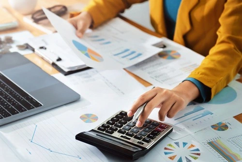 Person using a calculator while reviewing documents, illustrating how cerebral palsy settlements are calculated.