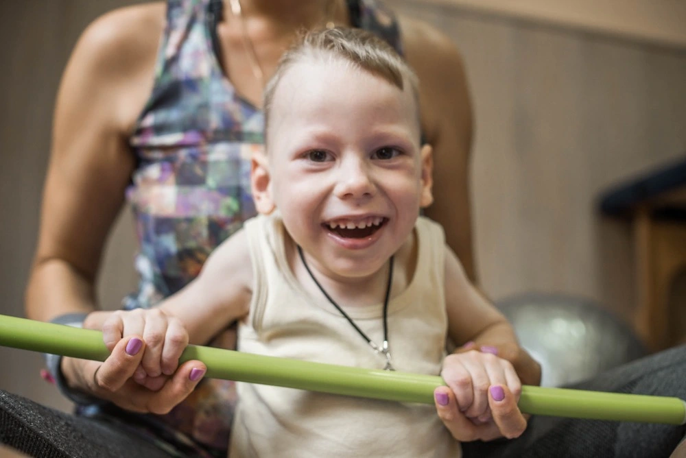 Child participating in physical therapy with a parent present, illustrating support for long-term health and care in cerebral palsy cases.