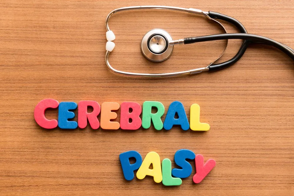 Wooden letter blocks spelling “cerebral palsy” beside a stethoscope, illustrating what cerebral palsy is and its medical context.